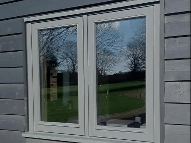 Painted casement window in a grey clad wall